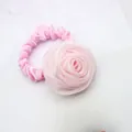 Detail of soft pink chiffon rose hair tie with elegant silk texture on marble surface - Pink