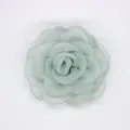Detalle macro del broche de camelia en organza verde claro con pétalos ondulados en capas - Azul Agua