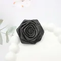 Detalle de una rosa de tela negra con elegantes acabados en purpurina dorada - Base plana / Negro