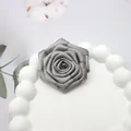 Primer plano de una rosa de tela gris plateada hecha a mano con hilos dorados y capas - Base plana / Gris