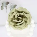 Detailed close-up of a handmade 10cm olive green satin peony flower on a white wavy pedestal - Grey Green