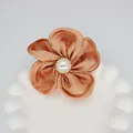Détail d'un accessoire fleur en satin champagne fait main avec une perle centrale - Base plate / Orange Tamisé