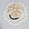 Detailed macro view of champagne satin flower hair tie with central white pearl accent - Beige