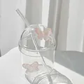 Detail shot of a transparent glass cup with pink butterfly charms and a dome lid - Pink Butterfly