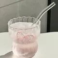 Macro view of clear glass coffee cup with pink butterfly detail and glass straw - Patterned Butterfly Cup With Straw