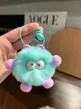 Close-up of mint green plush monster keychain with purple ears and a bell detail - Light Blue