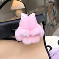 Pink rabbit fur bag charm with polka dot bow displayed on a canvas shoulder bag - Pink