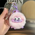 Pink plush monster keychain with purple silicone accents shown in use on a car key - Purple