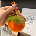 Dettaglio del portachiavi a forma di caco in peluche arancione con ciondolo portafortuna - I Sogni Si Avverano