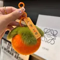 Dettaglio del portachiavi a forma di cachi in morbido peluche arancione e verde - Felicità Eterna