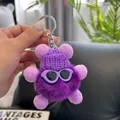 Close-up of purple plush soot sprite keychain with sunglasses and knitted hat - Deep purple