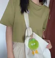 Detail of light green plush monster keychain with big eyes on a white handbag - Premium Green