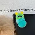 Dettaglio di un portachiavi a bruco in peluche soffice verde e blu appeso a una borsa nera - Ciano