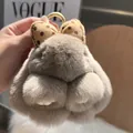 Close-up of fluffy plush rabbit keychain with brown polka dot bow and gold metal ring - Brown