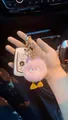 Pink plush duck keychain with purple ears and gold rhinestone clasp on car background - Light Purple