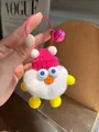 Close-up of white plush duck pendant with pink knit hat, bell and metal wire ring - White