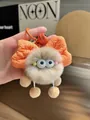 Close-up of beige plush pompom keychain with orange bow and matching bell accessory - Khaki Orange