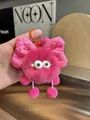 Detailed view of plush pink pompom keychain with oversized bow and small pink bell - Berry Pink
