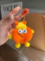 Detail eines weichen orangefarbenen Plüschenten-Anhängers mit gelber Mütze und Glocke - Orange
