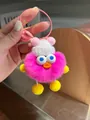 Detail von rosarotem flauschigem Monster-Schlüsselanhänger mit blauen Augen und Mütze - Fuchsia