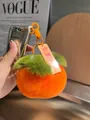 Dettaglio portachiavi in peluche a forma di cachi con moschettone e ciondolo in acrilico - Buone Notizie Successive