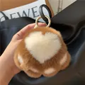 Close-up of cat paw plush keychain with white heart pattern and gold ring on black bag - Caramel color