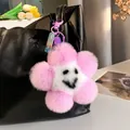 Pink and white plush flower keychain with smiling face on a black leather handbag - Taro Purple