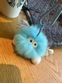 Close-up of fluffy light blue plush monster keychain with white leather wings on wooden table - Sky Blue
