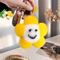 Macro detail of plush sunflower keychain with smiling face and golden ring attachment - Yellow