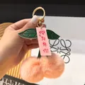 Detalle de llavero de cereza de felpa rosa con hojas de cuero sintético y gancho dorado - Nude