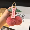 Llavero de cereza de felpa rosa con hojas verdes y clip de metal dorado en fondo de madera - Rosa Palo
