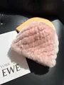 Detail of pink knitted rabbit fur hat with striped texture on a studio background - Pink