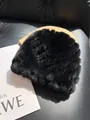 Detail of premium black faux fur hat showing dense plush texture on leather sofa background - Black