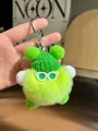 Detail of green furry doll with white hands, sunglasses, beanie, and silver keychain - Green
