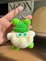Detail of cute plush keychain with green knit hat and sunglasses on wooden background - Off White