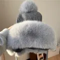 Dettaglio del cappello in maglia grigia con grandi pompon in finta pelliccia sulle orecchie - Taglia unica / Grigio