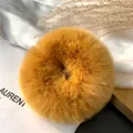 Close-up of ginger plush faux fur scrunchie with fluffy texture on white fabric - Warm Yellow