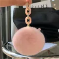 Close-up of pink faux rabbit fur keychain with cute cat ears and gold metal chain links - Nude Pink