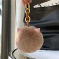 Close-up of soft faux fur cat ear keychain with elegant gold and resin links detail - Coffee