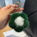 Close-up of a green and white plush flower keychain with gold hardware on a bag - Army Green
