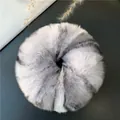 Detail of a fluffy grey and white faux rabbit fur scrunchie on a dark textured surface - White Grey Leopard