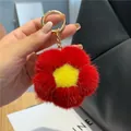 Détail d'un porte-clés fleur en fourrure de vison rouge avec anneau doré sur sac noir - Rouge