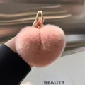 Macro detail of heart-shaped plush keychain in soft pink rex rabbit fur with gold ring - Nude Pink