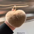 Close-up of heart-shaped faux fur keychain in light brown with golden metal ring - Brown