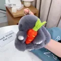 Gros plan d'un porte-clés lapin en peluche grise avec carotte tenu à la main - Gris clair
