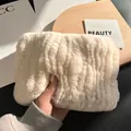 Detail showing plush cream faux fur texture and striped wavy pattern on hand-held pouch - Off White