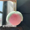 Close-up of pink and green plush peach keychain with golden circular metal hook - Light Pink (Water-drop Buckle)