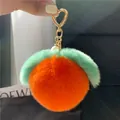 Detail eines flauschigen Pfirsich-Anhängers in Orange mit goldenem Herz-Verschluss - Leuchtend Orange Ball (Herzschließe)