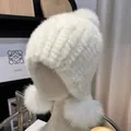 Detailed knit texture of white mink fur hat with plush fox fur pompoms and ear flaps - One Size Stretchy / White