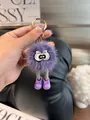 Close-up of purple faux fur monster keychain with long legs and cute big eyes - Purple